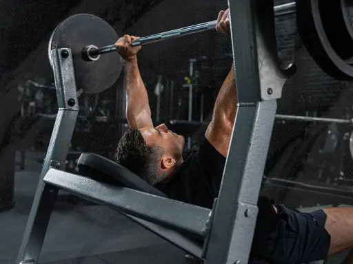 Mann beim Bankdrücken, ein wichtiger Teil seines Powerlifting Trainingsplans.