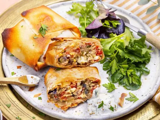 Deux bricks au thon croustillantes, garnies d'une farce savoureuse, servies avec une salade fraîche et une sauce crémeuse.