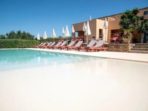 Agriturismi con piscina: lettini prendisole e ombrelloni invitano al relax in un contesto rurale.