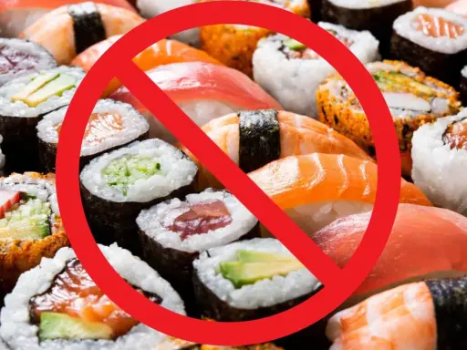 Rotes Verbotsschild über Sushi und Maki-Rollen. Achtung: verbotene Lebensmittel Schwangerschaft.