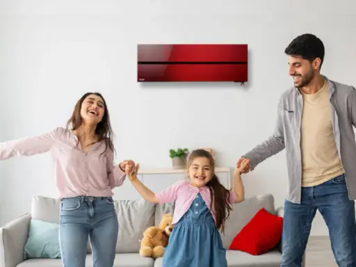 Familia feliz bailando bajo un aire acondicionado inverter rojo, disfrutando del confort y bajo consumo kwh.