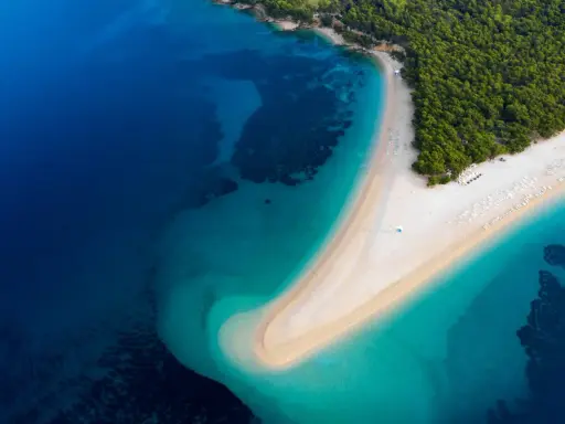 Widok z lotu ptaka na Zlatni Rat w Chorwacji. Plaże otoczone turkusowym morzem i zielonym lasem.