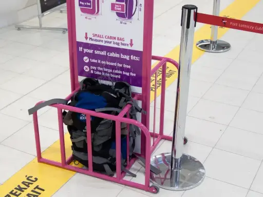 Wizzair leki w bagażu podręcznym? Sprawdź wymiary w różowym stojaku. Plecaki czekają na pomiar.