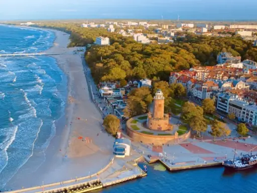 Malownicze miejscowości nad morzem z latarnią morską, plażą i portem.