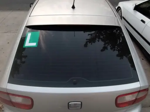 El coche plateado tiene una L verde en el lado izquierdo de la ventana trasera, indicando que el conductor está aprendiendo.