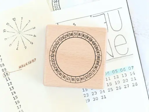 Holzstempel mit Kreis und Zahlen für den koptischen Kalender, daneben eine handgezeichnete Monatsübersicht.