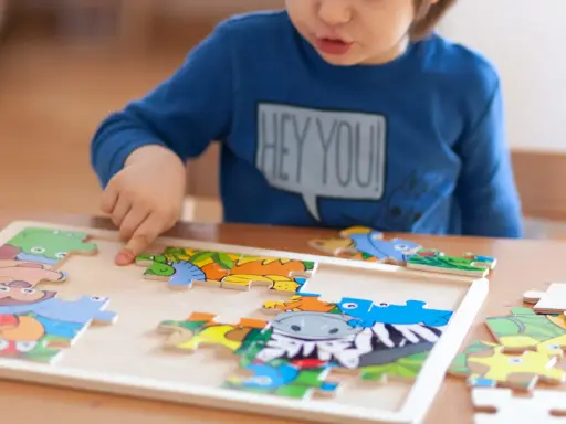 Chłopiec układa kolorowe puzzle ze zwierzątkami. Ukladanie puzzli co ćwiczy? Rozwija spostrzegawczość i zdolności manualne.