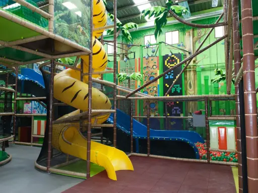 Un divertido parque infantil en Madrid con toboganes amarillos y azules, rocódromos y una piscina de bolas.