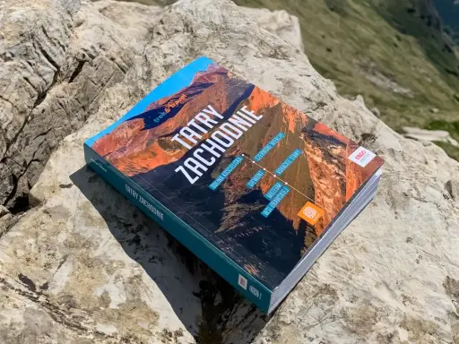 Przewodnik "Tatry Zachodnie" leży na skale. Na okładce widnieje m.in. Dolina Kościeliska.