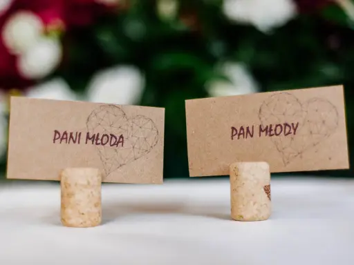 Urocze winietki ślubne z sercami i napisami "Pani Młoda" i "Pan Młody", stojące na korkach od wina.