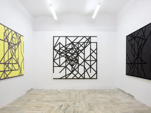 Galeria sztuki z trzema obrazami: żółtym, czarno-białym i czarnym, wszystkie w stylu abstrakcji w malarstwie, z geometrycznymi wzorami.