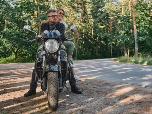 Para na motocyklu, ciesząca się słońcem i lasem podczas podróży motocyklem po Polsce.