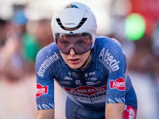 Juri Hollmann im Zeitfahr-Outfit, konzentriert auf der Strecke. Das blaue Trikot mit Alpecin-Logo und die aerodynamische Kopfbedeckung sind gut erkennbar.