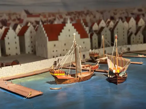 Modell av medeltida hamn i Visby. Skepp ligger vid kajen framför stadens karaktäristiska hus. En glimt av Visby historia.
