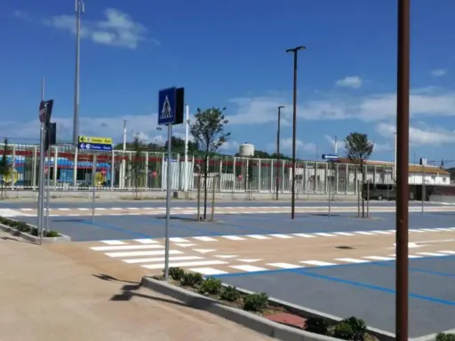 Parcheggio rimini con strisce pedonali e segnaletica, sullo sfondo un treno blu.