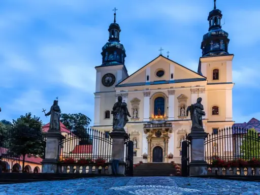 Imponująca bazylika na Kalwarii Zebrzydowskiej, z rzeźbami świętych przed bramą i wieżami w niebo.