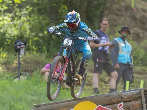 Troy Brosnan springt mit seinem Downhill-Bike über eine Holzrampe, bereit für den nächsten Sprung.