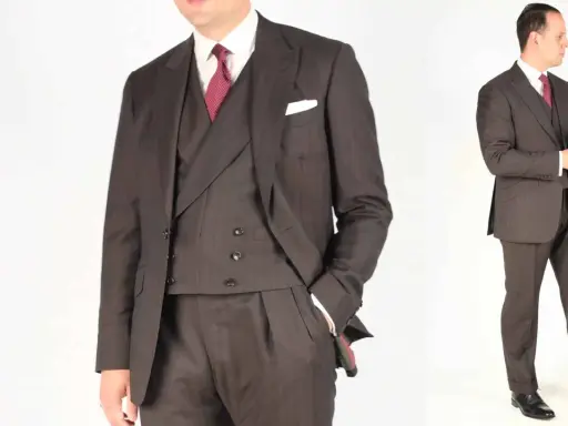 A man in a dark pinstripe suit, white shirt, and red patterned tie. He's adjusting his cuff, ready for a formal event.
