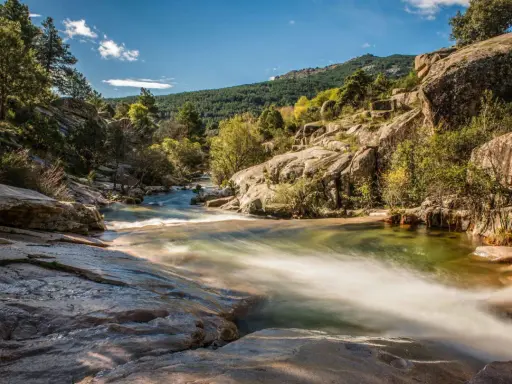 Río serpenteante entre rocas y vegetación, ideal para excursiones cerca de Madrid. Un paisaje natural de ensueño.