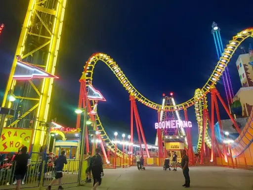 Wiedeń wesołe miasteczko nocą. Kolejka Boomerang i wieża zjeżdżalni w blasku neonów.