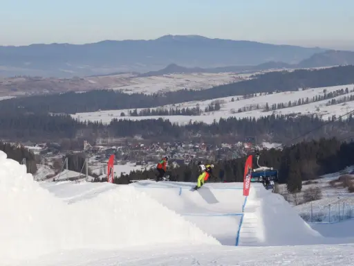 Snowboardziści na stoku, idealne miejsce, gdzie na narty z Wrocławia. W tle góry i miasteczko.