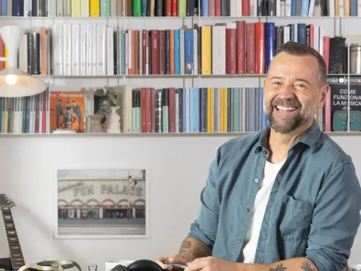 Fabio Volo sorride tra gli scaffali pieni di libri, forse in attesa di presentare il suo ultimo libro.