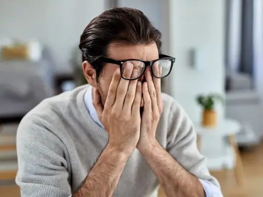 Mann mit Brille reibt sich die Augen, wirkt gestresst. Manche glauben, rauchen hilft gegen Stress, doch das ist ein Trugschluss.