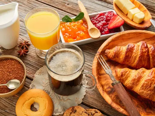 Pyszne śniadanie kontynentalne: świeże croissanty, dżemy, masło, sok pomarańczowy i kawa. Idealny początek dnia!