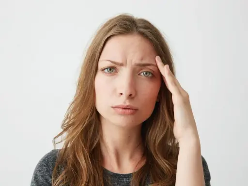 Donna con mano sulla tempia, espressione preoccupata, forse per lo stress ossidativo della pelle.