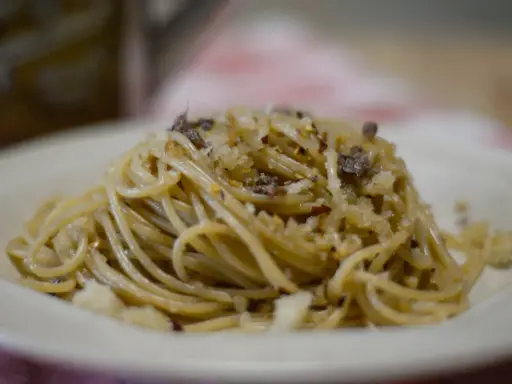 Un piatto di spaghetti conditi con pangrattato tostato, aglio, peperoncino e formaggio grattugiato, un classico della pasta mollicata.