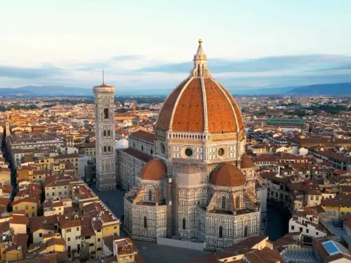 Vue aérienne de la **cattedrale Santa Maria** del Fiore et de son campanile, dominant les toits de Florence au lever du soleil.