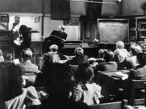 Lehrer mit Stock ermahnt Schüler in einer Klasse, die an eine Schule im Mittelalter erinnert.