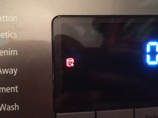Pralka Samsung wyświetla czerwony symbol bębna z kryształkami, wskazujący na problem z odprowadzaniem wody. To jeden z kodów błędów.