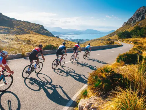 Ciclisti su una strada panoramica, esplorando i più bei percorsi in bicicletta in Italia, con il mare e le montagne sullo sfondo.