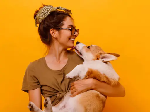 Uśmiechnięta dziewczyna z pieskiem corgi. Szukasz imiona dla psa na B? Może Borys albo Bąbel?