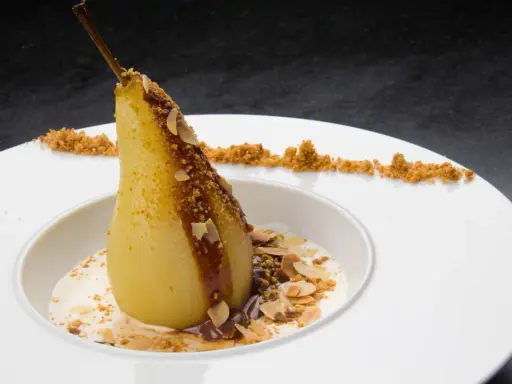 Un poire pochée, nappée de chocolat et amandes effilées, servie avec une crème légère. Un dessert poire chocolat rapide et gourmand.