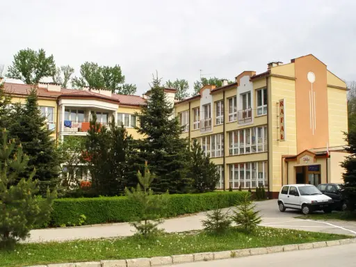 Sanatorium Rafał Busko Zdrój, z żółtą fasadą i zielenią wokół, zaprasza na wypoczynek.