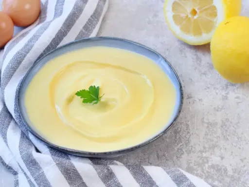 Cremige Joghurt-Mayonnaise mit Zitrone und Petersilie, daneben Eier und Zitronen.