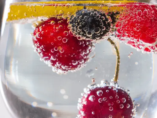 Erfrischendes Getränk mit Kirschen, Blaubeeren und Zitrone in sprudelndem Wasser. Der Unterschied Sodawasser und Mineralwasser liegt in der Kohlensäure.