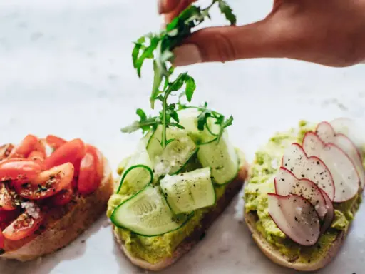 Tres tostadas gourmet: tomate, pepino y aguacate con rábano. La mejor variedad de aceite de oliva para tostadas realza sus sabores.