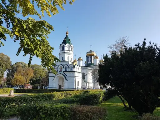 Biała cerkiew ze złotymi kopułami, otoczona zielenią. Piękny widok na szlak tatarski w słoneczny dzień.