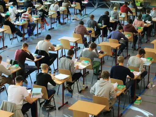 Schüler konzentriert bei einer Prüfung. Die Wortherkunft des Abiturs ist lateinisch, was "weggehen" bedeutet.