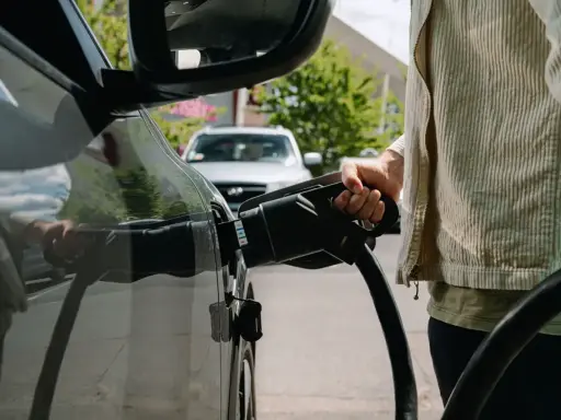 Persona che collega il cavo di ricarica a un'auto elettrica, pensando alle tariffe ricarica auto elettrica.