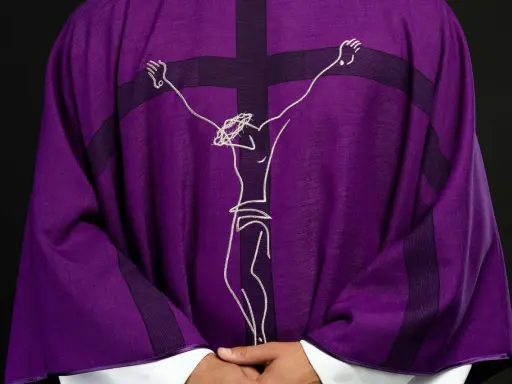 Fioletowa szata liturgiczna z haftowanym wizerunkiem Jezusa na krzyżu.