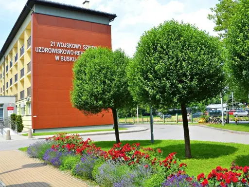 Sanatorium MSW Busko Zdrój z czerwonymi różami i lawendą w słoneczny dzień.