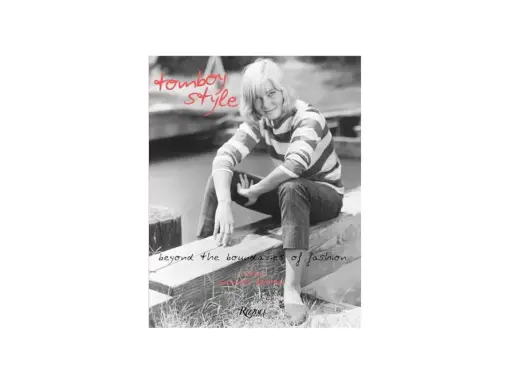 A woman with short blonde hair embodies tomboy style, wearing a striped shirt and jeans, sitting on a wooden beam. Text reads "tomboy style" and "beyond the boundaries of fashion.