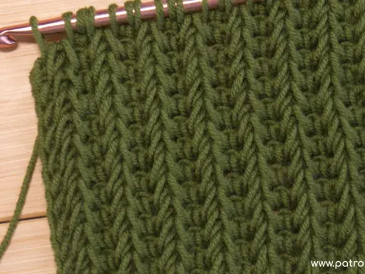 Punto tunecino con ganchillo en verde, ideal para mantas. El patrón crea un tejido denso y texturizado.