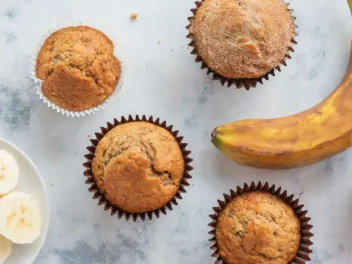 Saftige bananen muffins, ein reifer Banane und Bananenscheiben auf einem Teller. Perfekt für den Kaffeetisch.