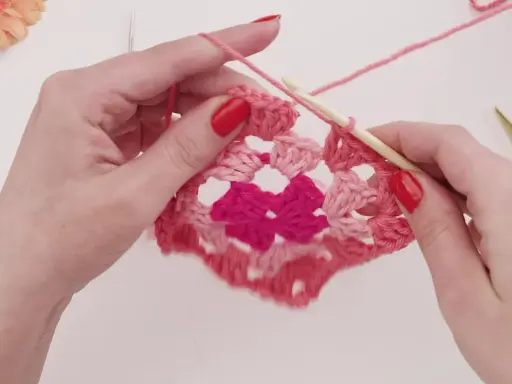 Händer virkar ett rosa virkat zigzag filt mönster med en virknål.