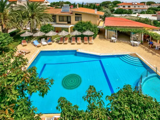 Basen hotelowy na Rodos, z leżakami i parasolami. Idealne miejsce na relaks pod słońcem.